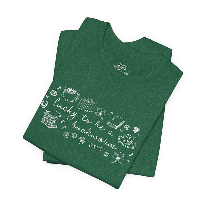 Green t-shirt with white font reading "lucky to be a bookworm" and line illustrations of St. Patrick's Day items and books on a white background