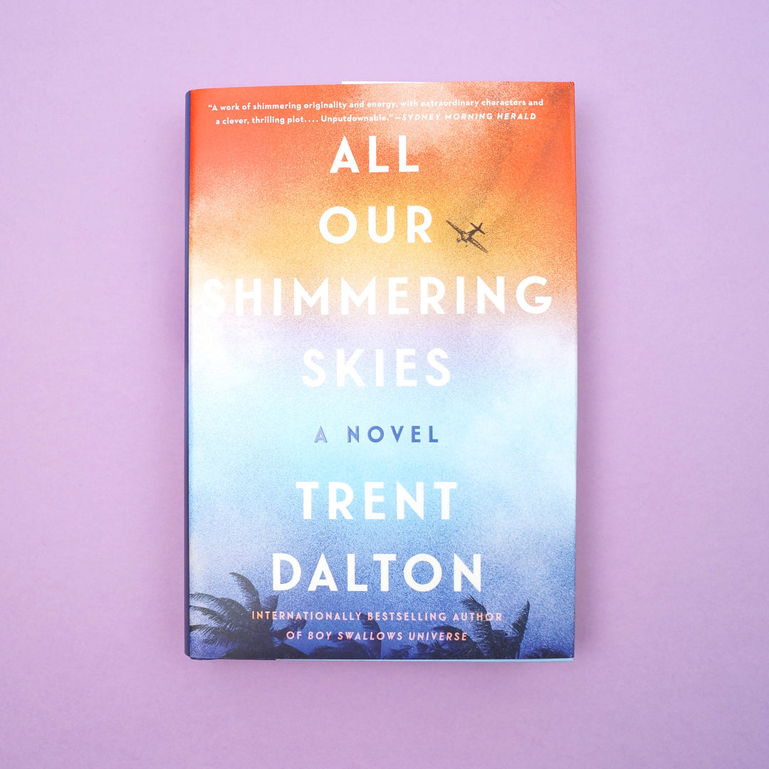 A hardcover copy of All Our Shimmering Skies by Trent Dalton.