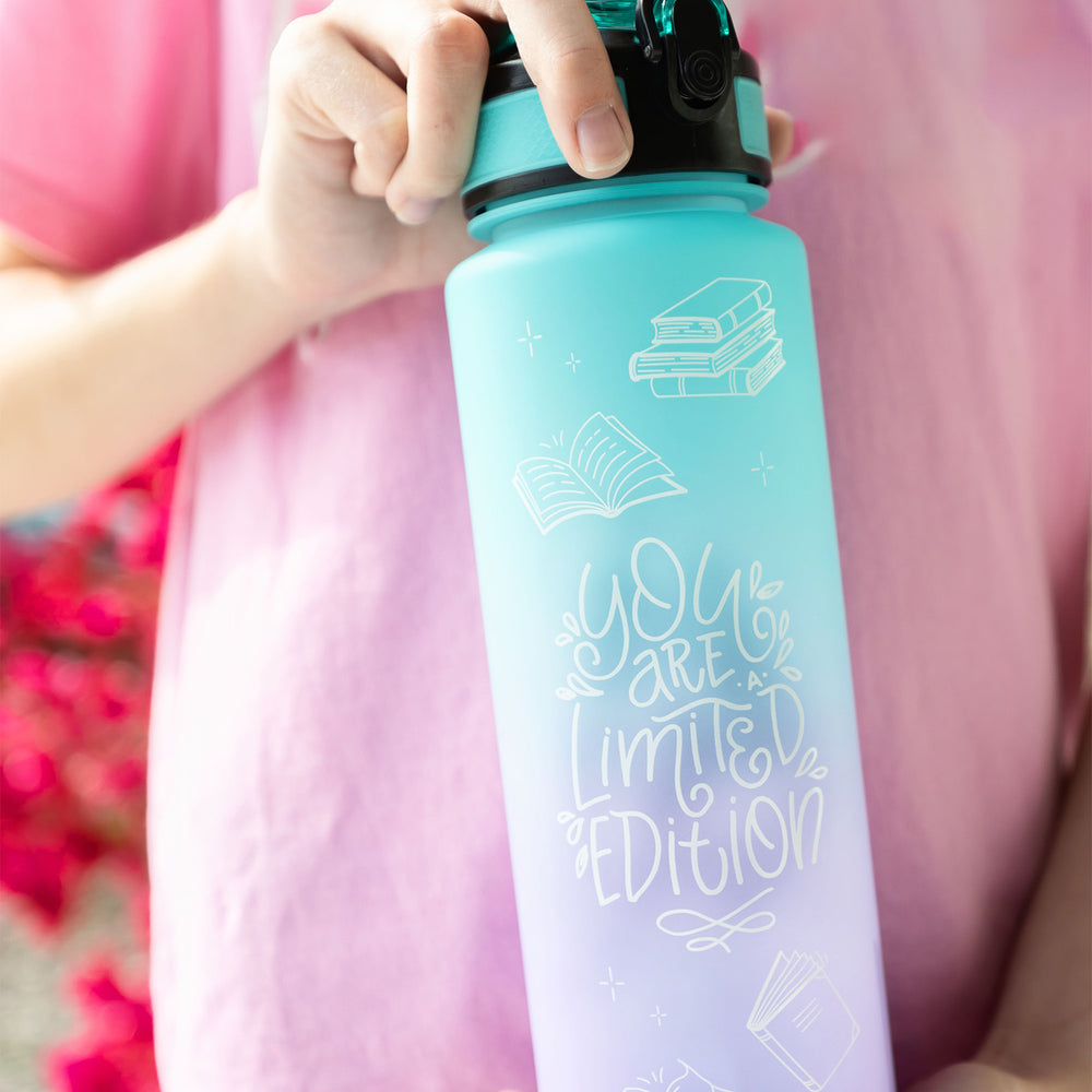 White hands hold a blue and purple ombre water bottle with black lid. It reads "You are a limited edition".