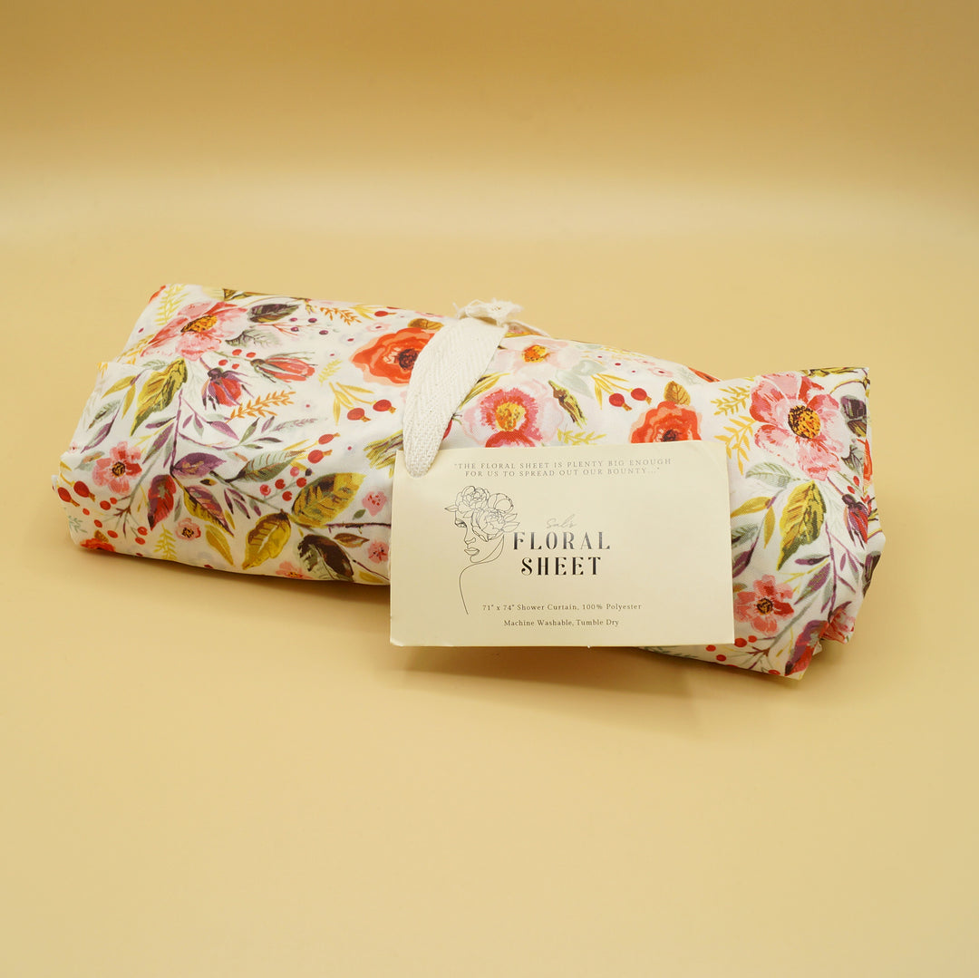 a floral-patterned shower curtain is rolled up with a tag on the front labeled floral sheet