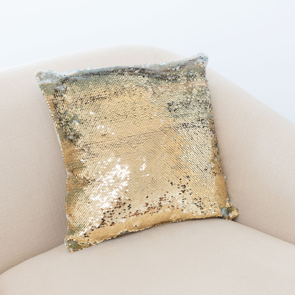 A gold sequin pillow on a pink chair.