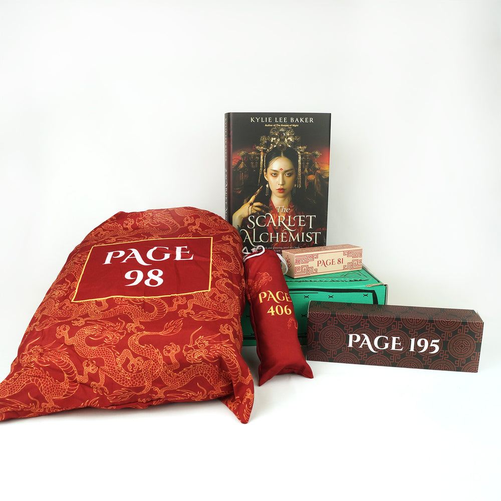 a large red drawstring bag is next to a small red tube-shaped drawstring bag, and a rectangular box. Behind these gifts is a hardcover copy of The Scarlet Alchemist and a small white/red box sitting on top of a green box. The boxes and bags all have page numbers.