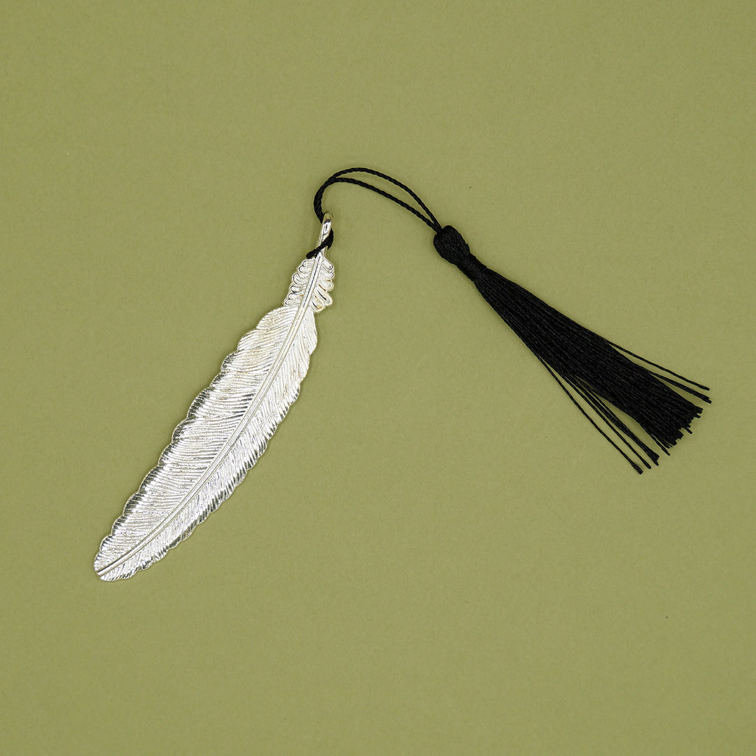 A silver feather bookmark with a black tassel. 