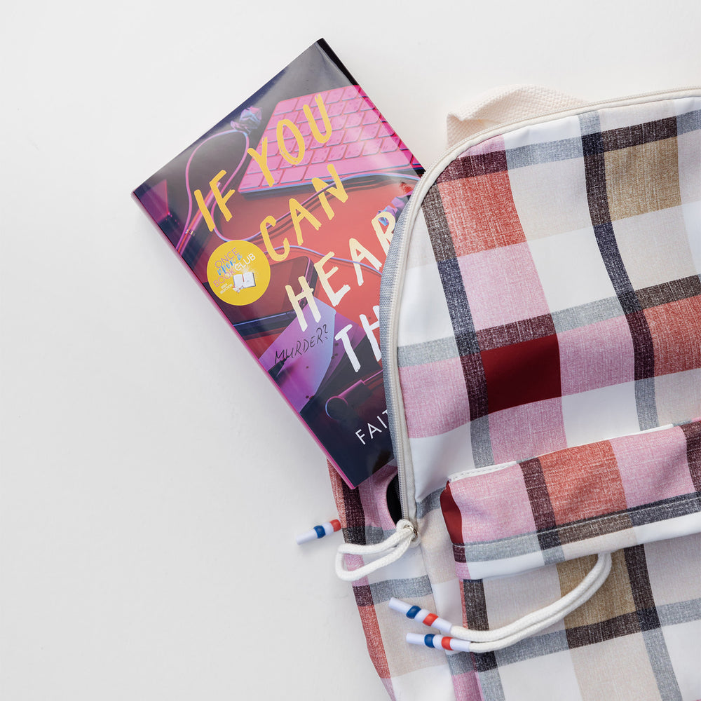 Plaid backpack with a book titled 'If You Can Hear This' on a light background