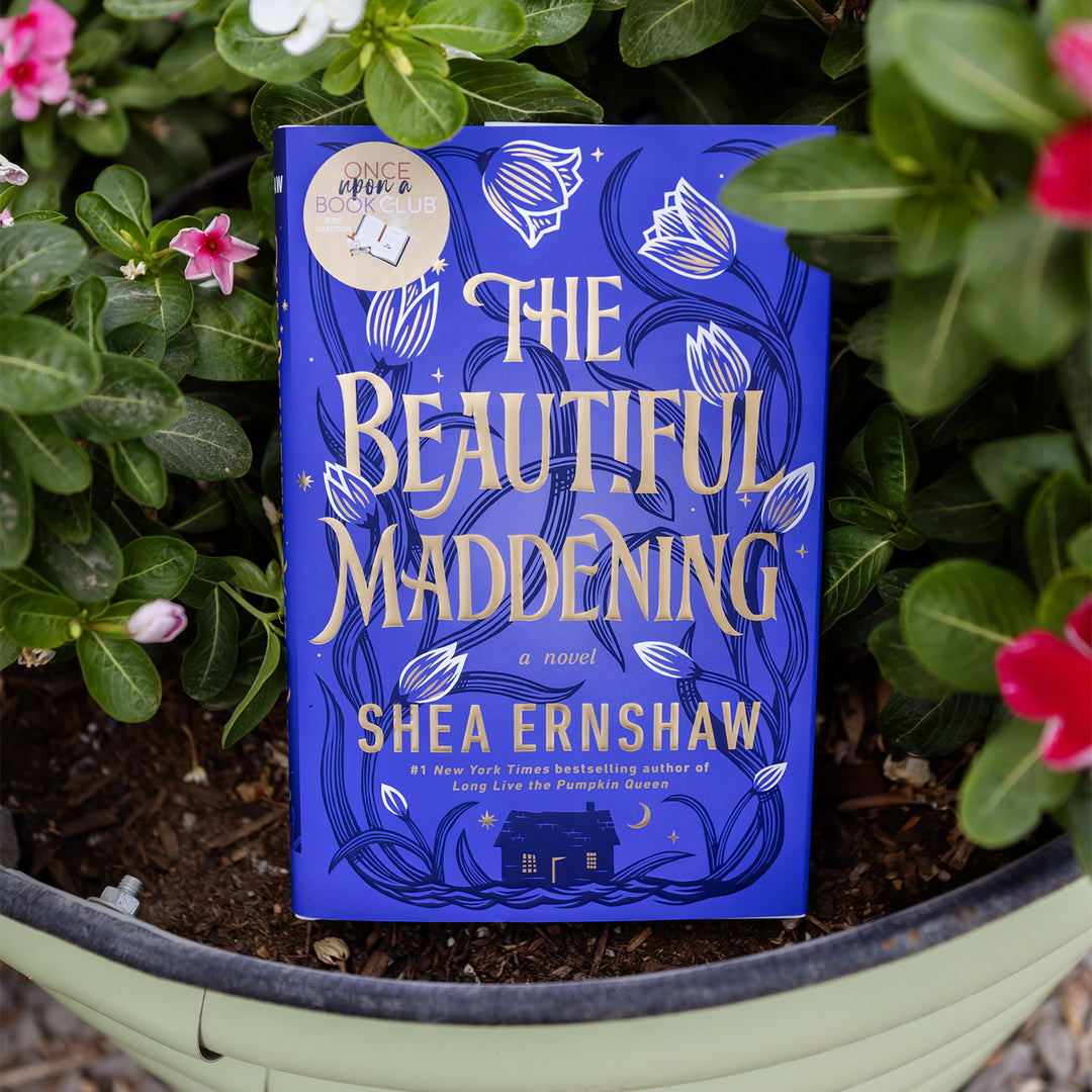Book titled 'The Beautiful Maddening' by Shea Ernshaw among plants