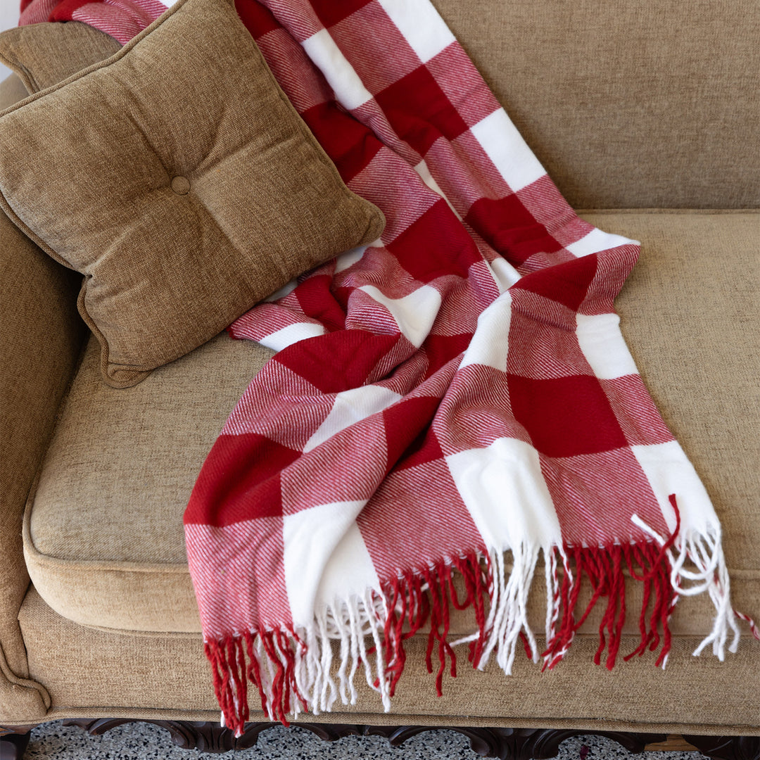 A red and white plaid blanket laying across a brown couch