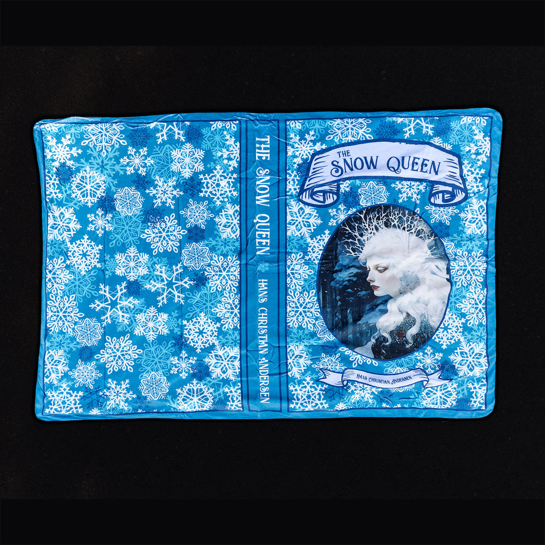 The outside of the Snow Queen blanket showcasing blue and white snowflakes and a portrait of the Snow Queen as well as the spine of the book.