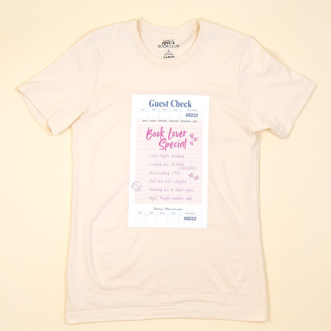 a cream t-shirt with a printed 'Book Lover Special' Guest Check design on a beige background