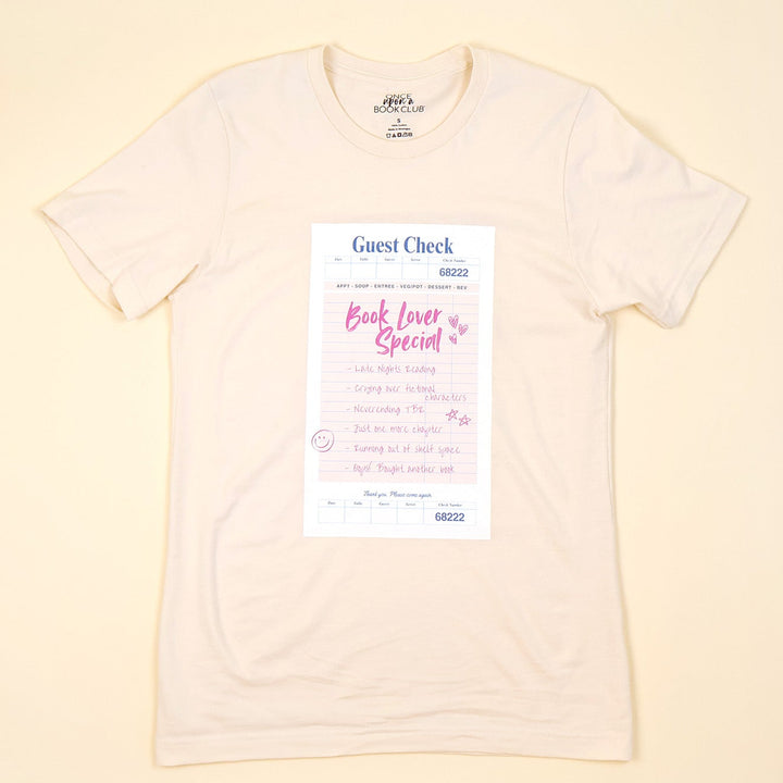 a cream t-shirt with a printed 'Book Lover Special' Guest Check design on a beige background