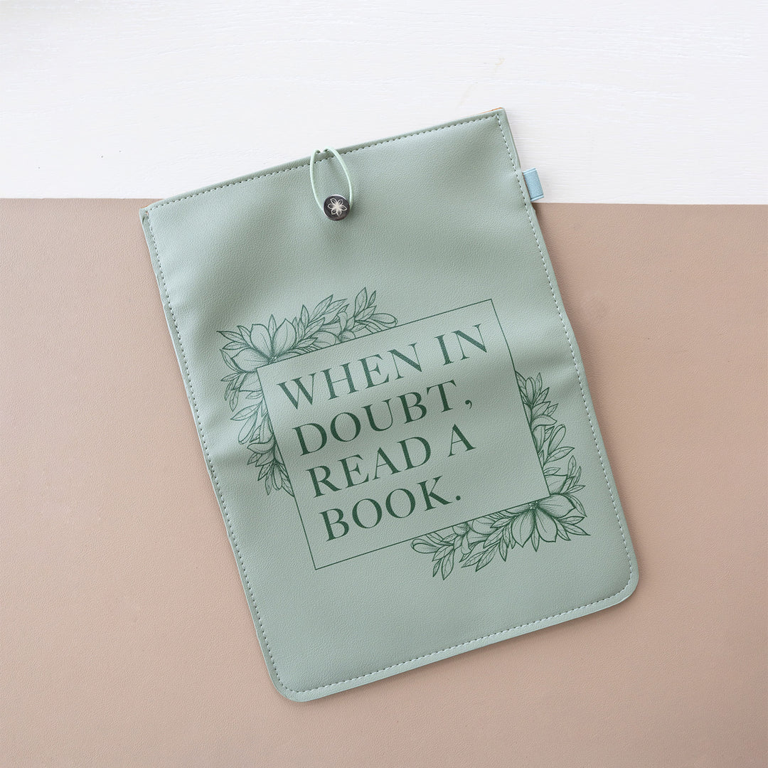 A booksleeve sits on a two-toned background. This booksleeve reads "When in doubt, read a book." in dark green font on a light green background and dark green floral details.