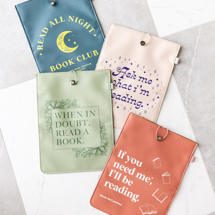 The set of four booksleeves featured in the Spring 2025 Once Upon a Book Club Boutique Collection. These book sleeves are titled "Read All Night", "What I'm Reading", "When in Doubt", and "Don't Need Me." These booksleeves lay on a checkered tile floor.