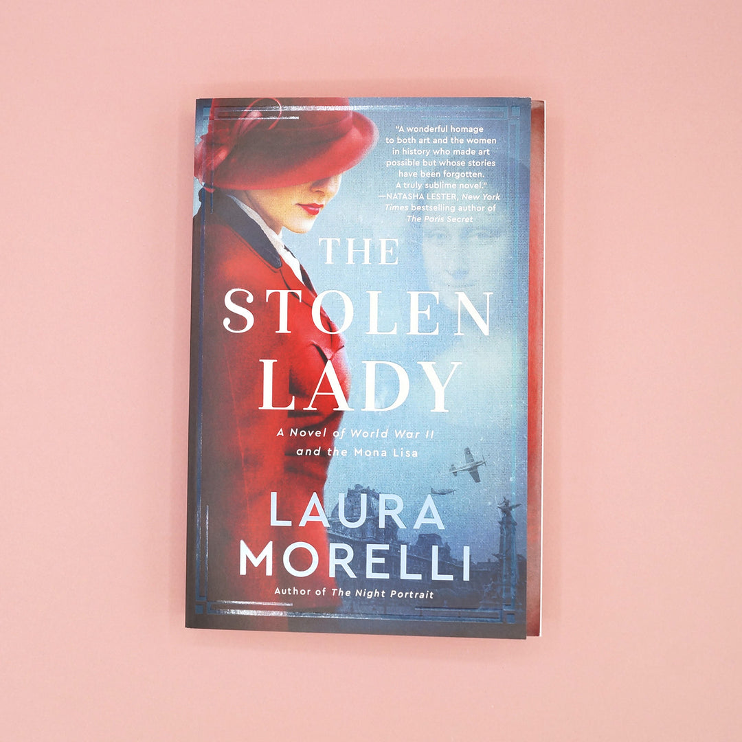 A paperback copy of The Stolen Lady by Laura Morelli on a pink background.