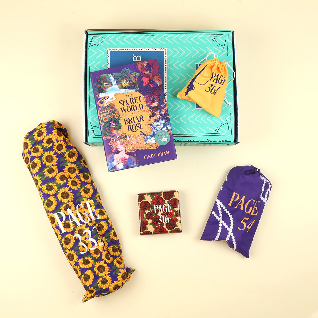A new deluxe hardcover copy of The Secret World of Briar Rose by Cindy Pham sits on a green OUABC box. Also pictured are four wrapped gifts labeled with page numbers to open as you read!