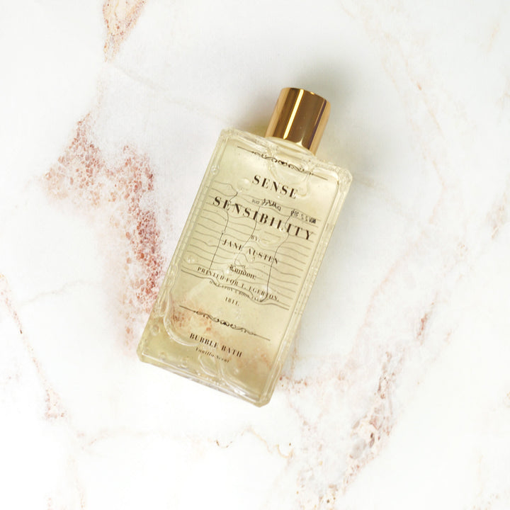 Sense and Sensibility bubble bath bottle with a gold cap displayed on a marble surface.