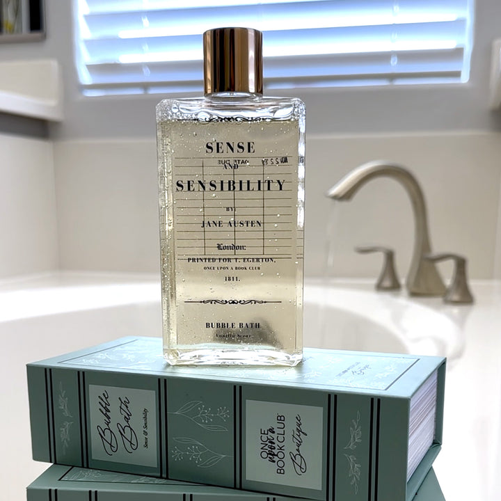 Sense and Sensibility bubble bath bottle displayed on decorative boxes near a bathroom sink.