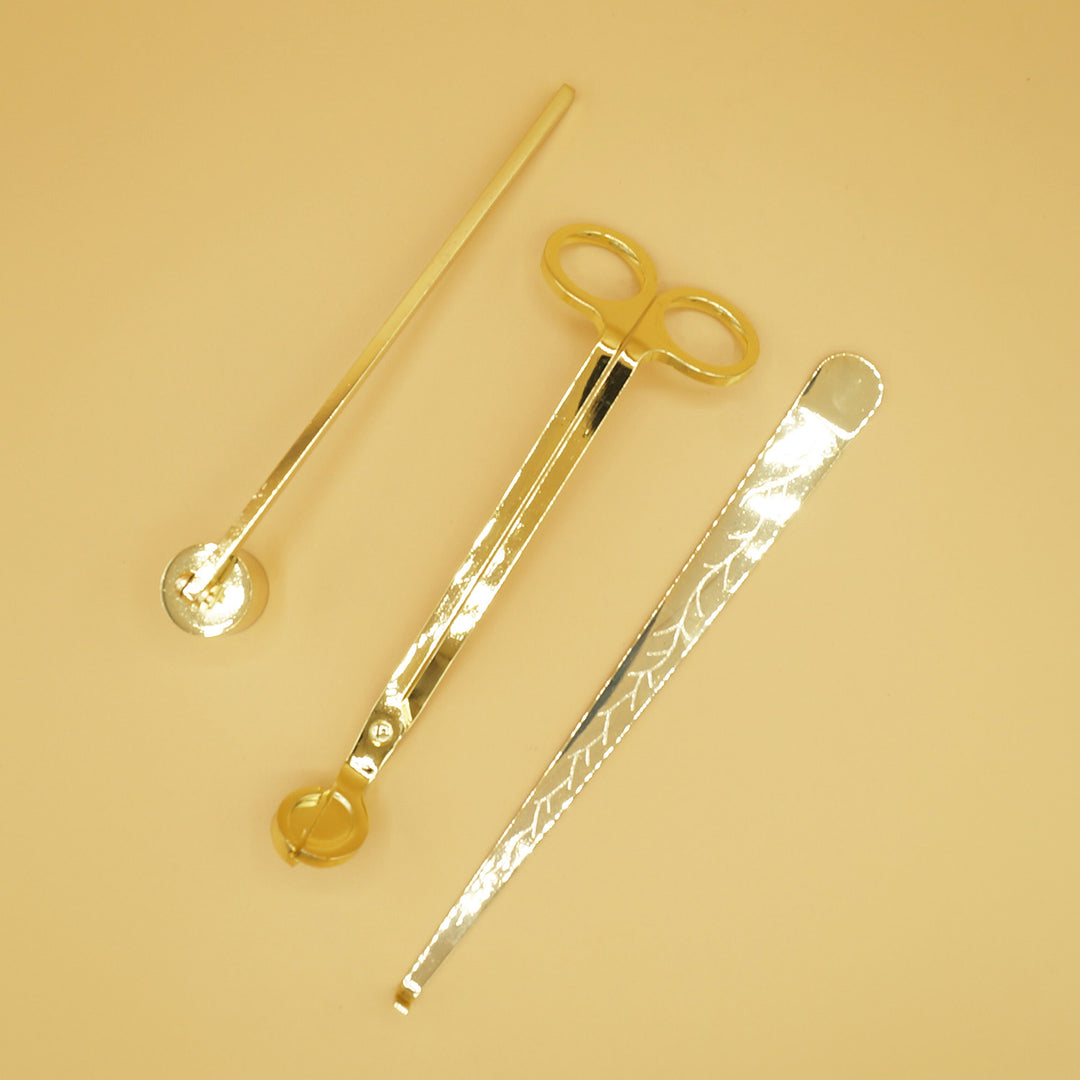 A gold candle care set - a wick trimmer, candle snuffer, and wick dipper