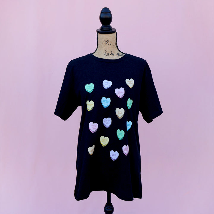 Black dress with colorful candy hearts with tropes on a mannequin against a pink background