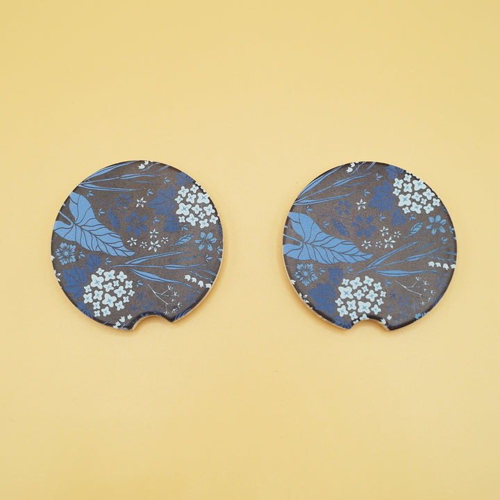 two black car coasters are next to each other with a pattern of blue leaves on them