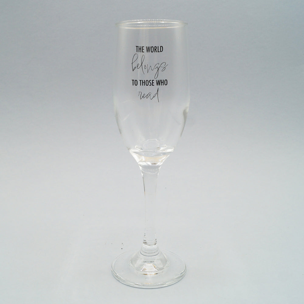 a clear champagne flute with the quote The World Belongs to Those Who Read