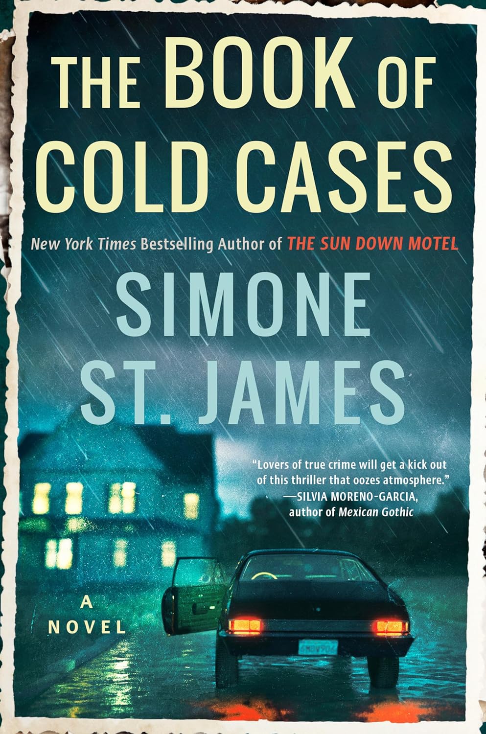 The book cover for The Book of Cold Cases by Simone St. James. The book cover has many blue tones and features a car with the brake lights on and the driver side door open in the rain. A house in the background has the windows illuminated.