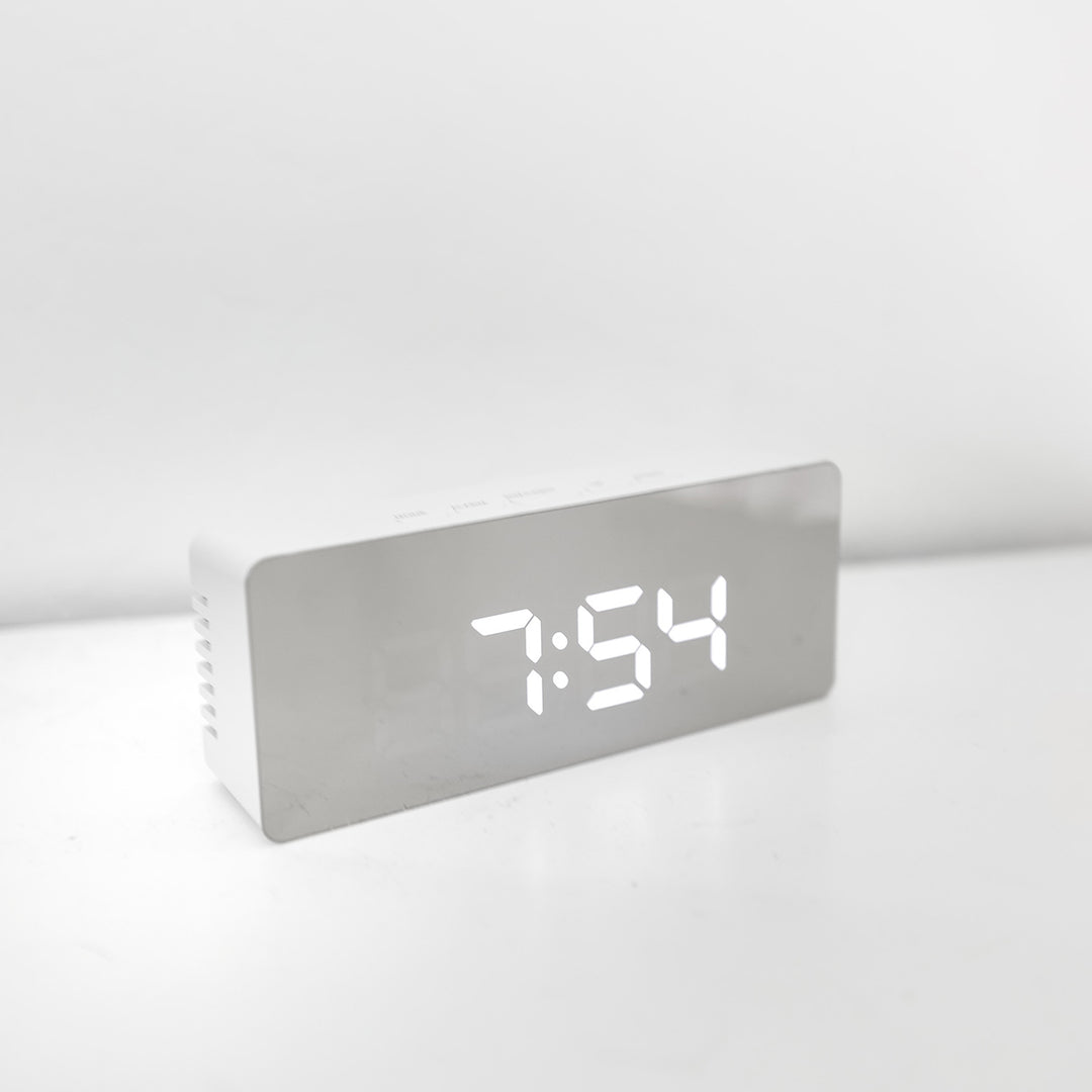 A silver alarm clock with the time at 7:54.