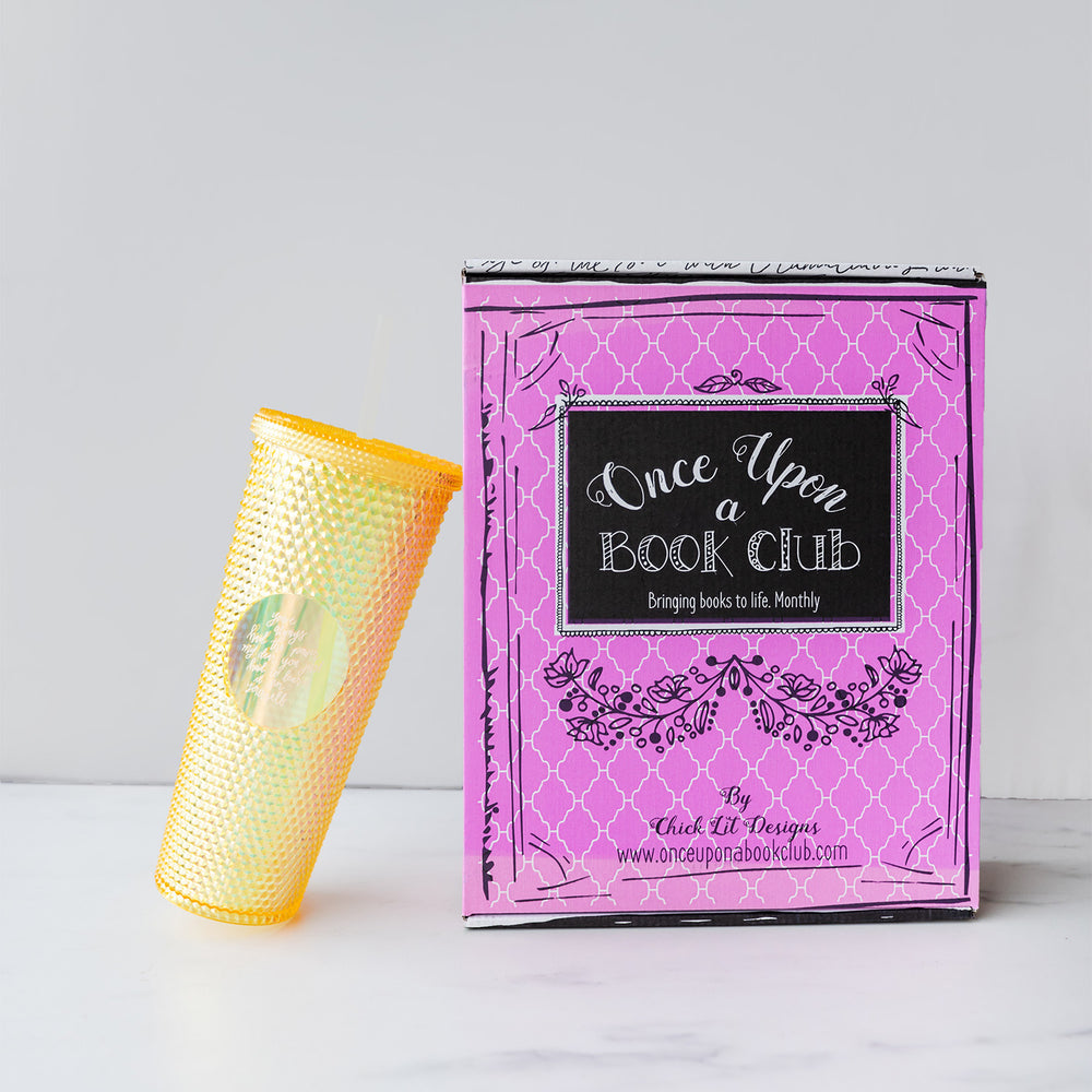 A yellow studded cup leans against a pink Once Upon a Book Club adult box.