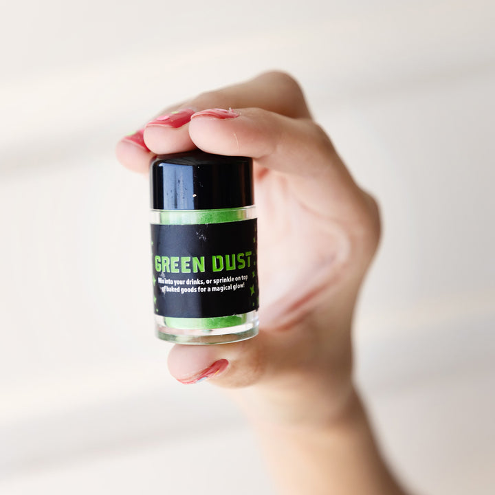 a hand holds up a jar of edible green shimmer dust.