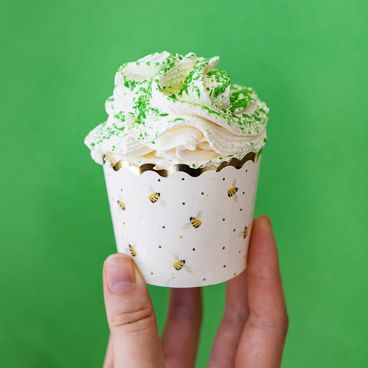 A hand holds up a cupcake that is decorated with the edible green shimmer dust.