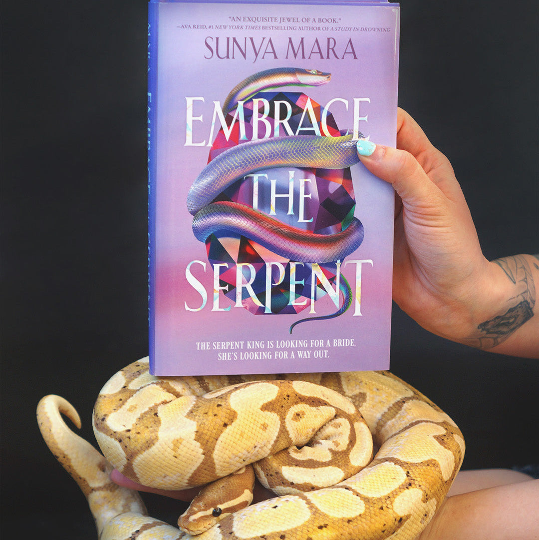 Book titled 'Embrace the Serpent' held by a hand with a snake on a dark background