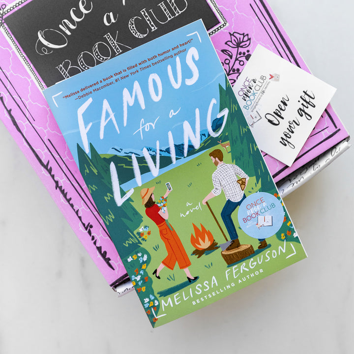 A paperback edition of Famous for a Living lays on a pink box next to an Open Your Gift sticker