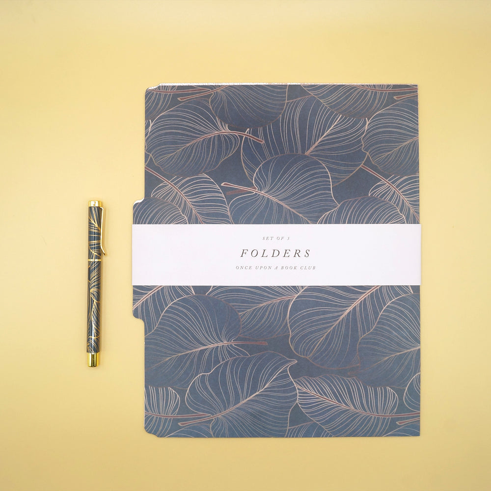 A leaf pattern, green and gold pen sits next to a bound set of three file folders featuring the same leaf pattern.