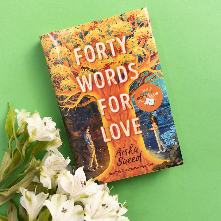 a hardcover copy of Forty Words for Love is next to white flowers on a green background