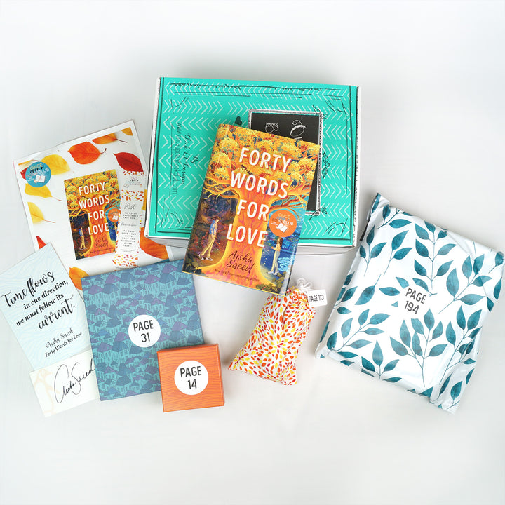 A hardcover edition of Forty Words for Love is on a green box. In front of the box, from left to right, is a signature card, quote card, bookclub kit, bookmark, blue box, orange square box, drawstring bag, and white bag with green leaves. The boxes and bags all have page numbers.