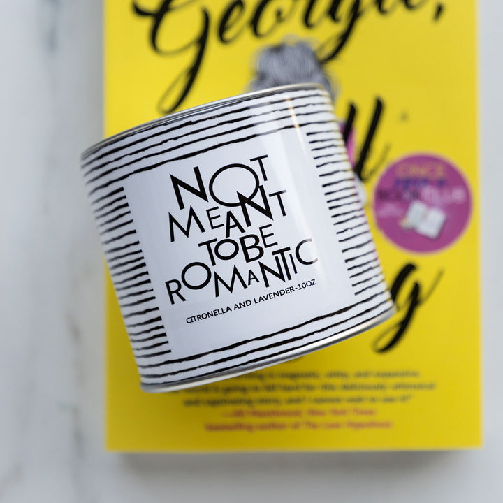 a black and white striped candle with the label Not Meant to be Romantic - citronella and lavender - 10oz is on a paperback edition of Georgie All Along