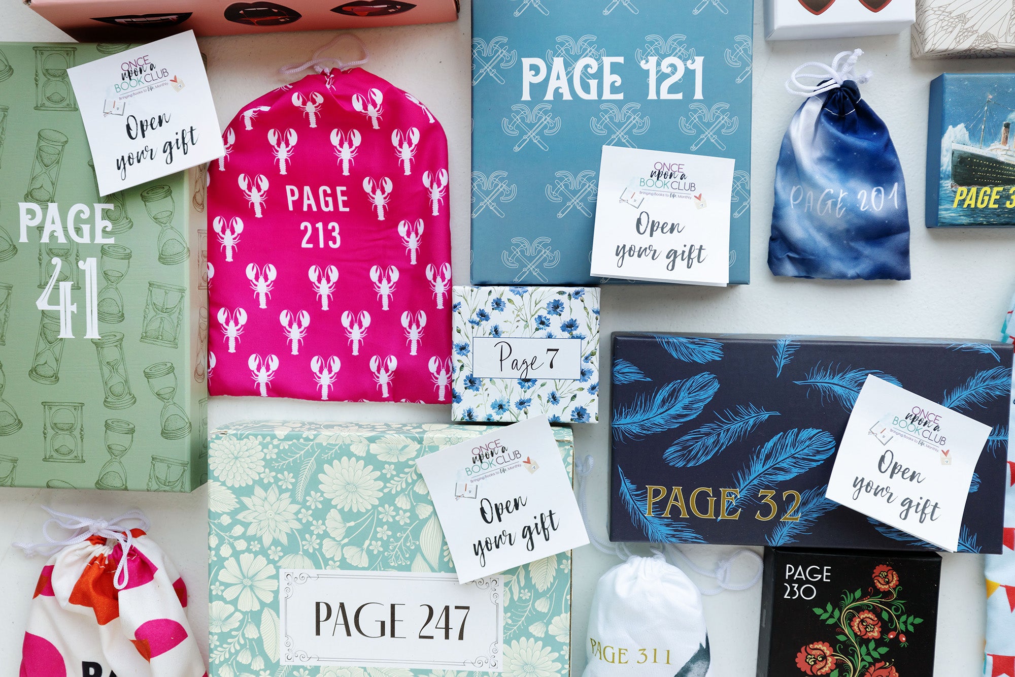 boxes and drawstrings bags of varying sizes and colors are in a flatlay image with multiple "open your gift" sticky notes over top of them