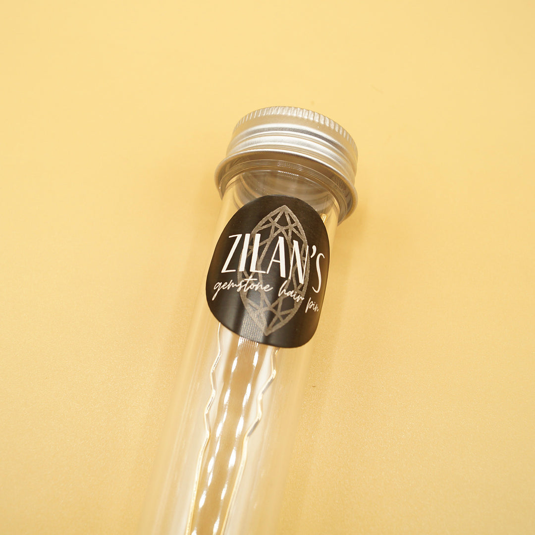a small tube labeled "Zilan's gemstone hair pin" sits on a yellow background