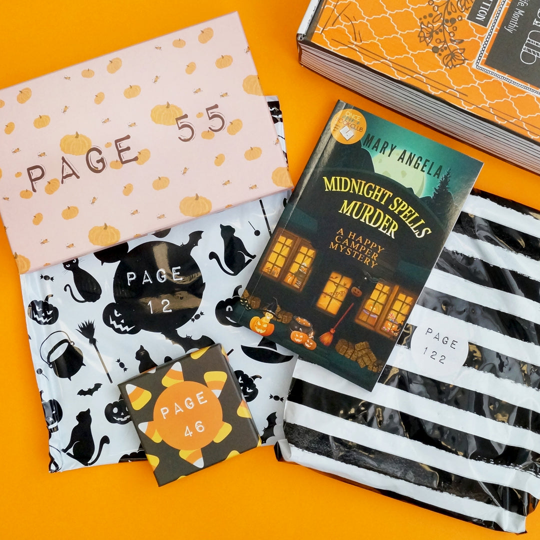 a paperback edition of Midnight Spells Murder by Mary Angela is below an orange box. Next to the book are an envelope with pumpkins on it, a square box with candy corn on it, and two black and white bags.