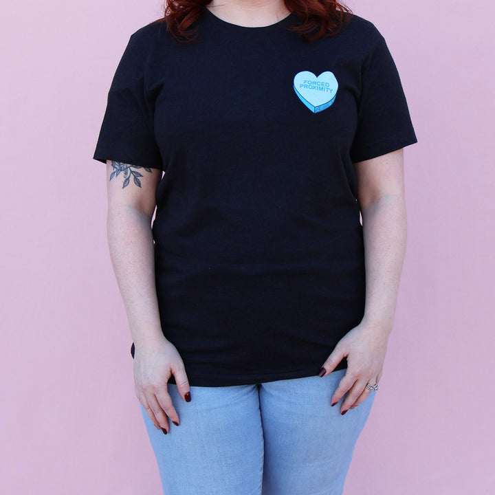Black t-shirt with a blue heart-shaped candy design and 'Forced Proximity' text on a pink background.