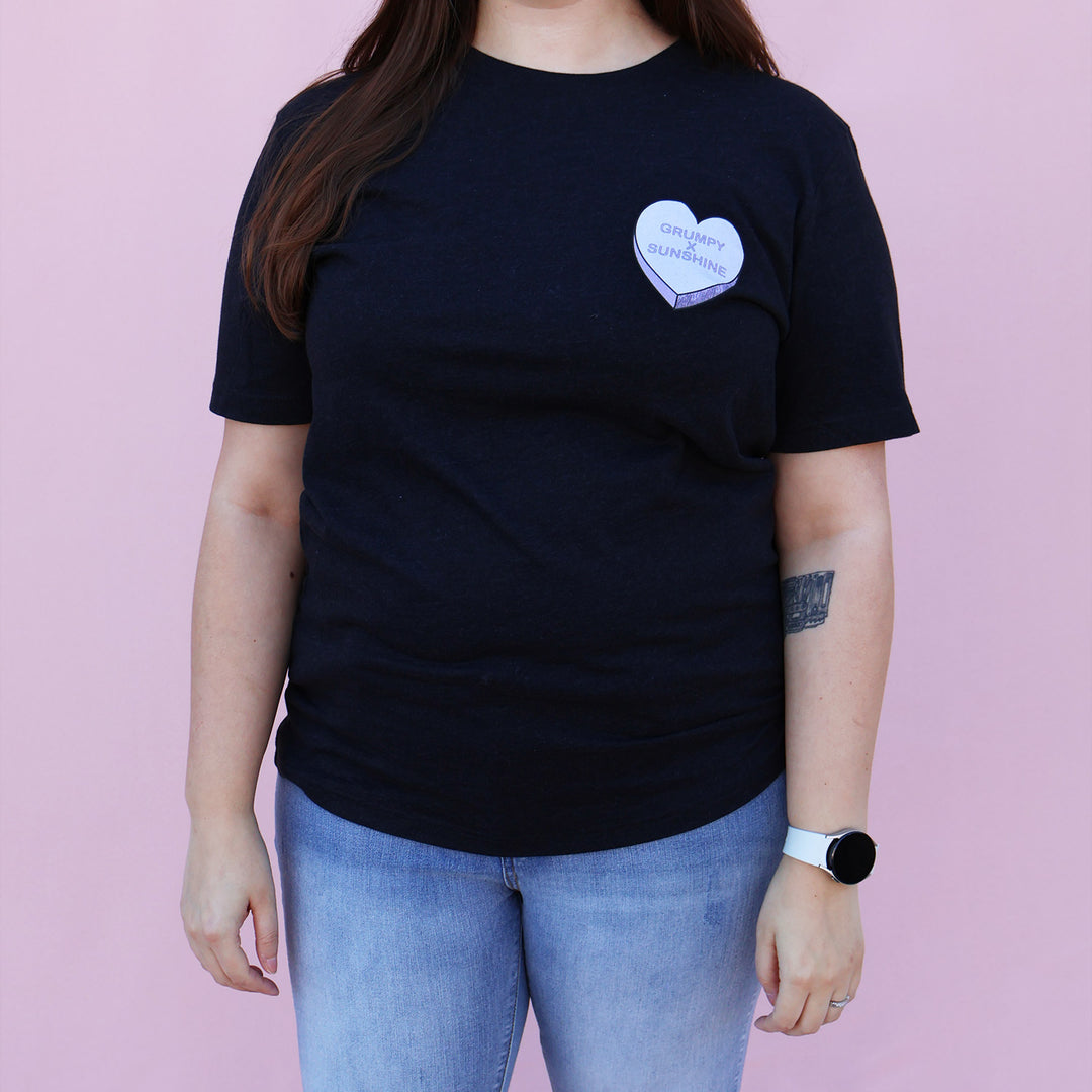 Black t-shirt with a purple heart-shaped candy design and 'Grumpy x Sunshine' text on a pink background.