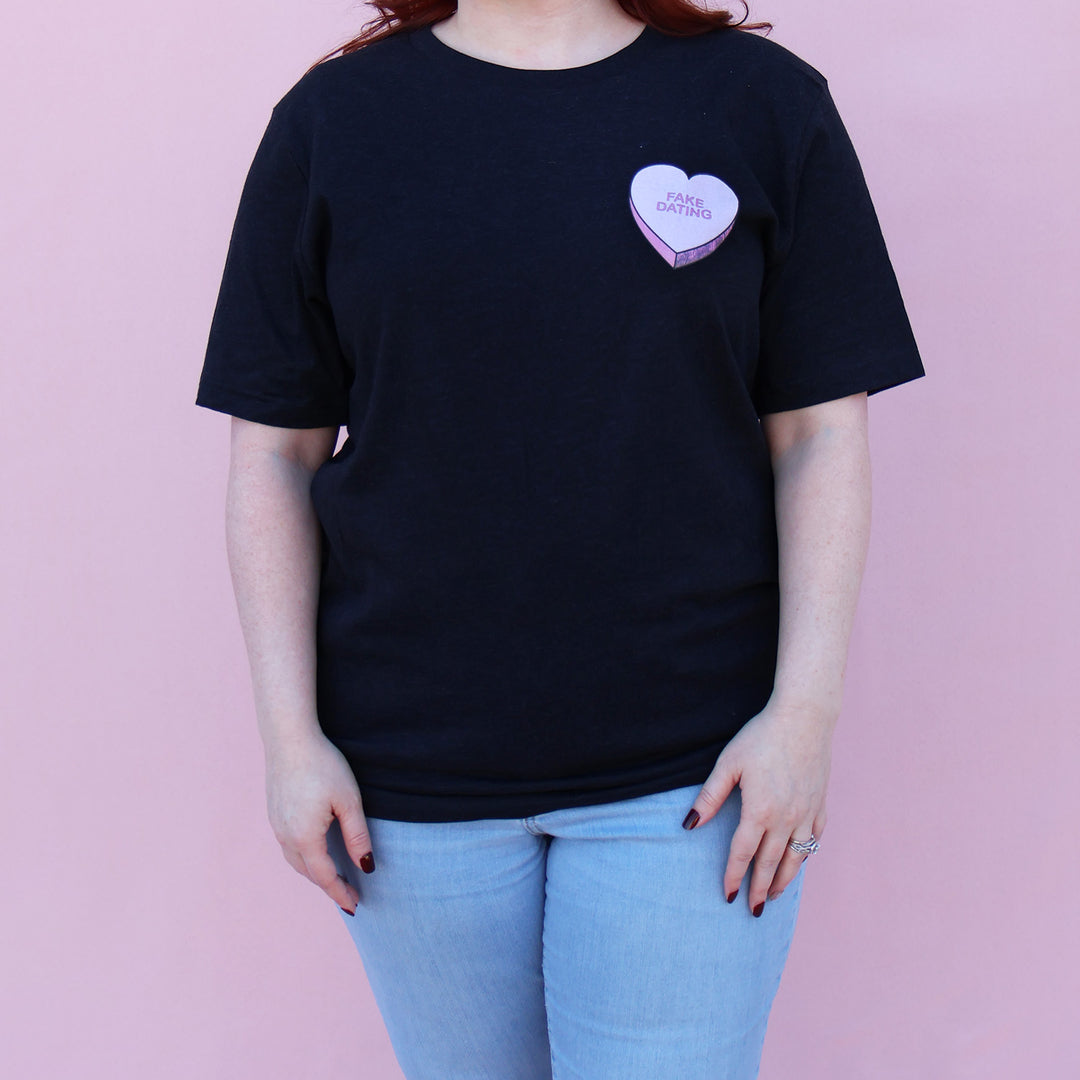 Black t-shirt with a pink heart-shaped candy design and 'FAKE DATING' text on a pink background.
