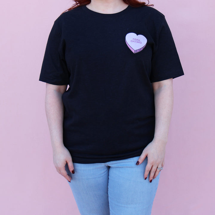 Black t-shirt with a pink heart-shaped candy design and 'FAKE DATING' text on a pink background.