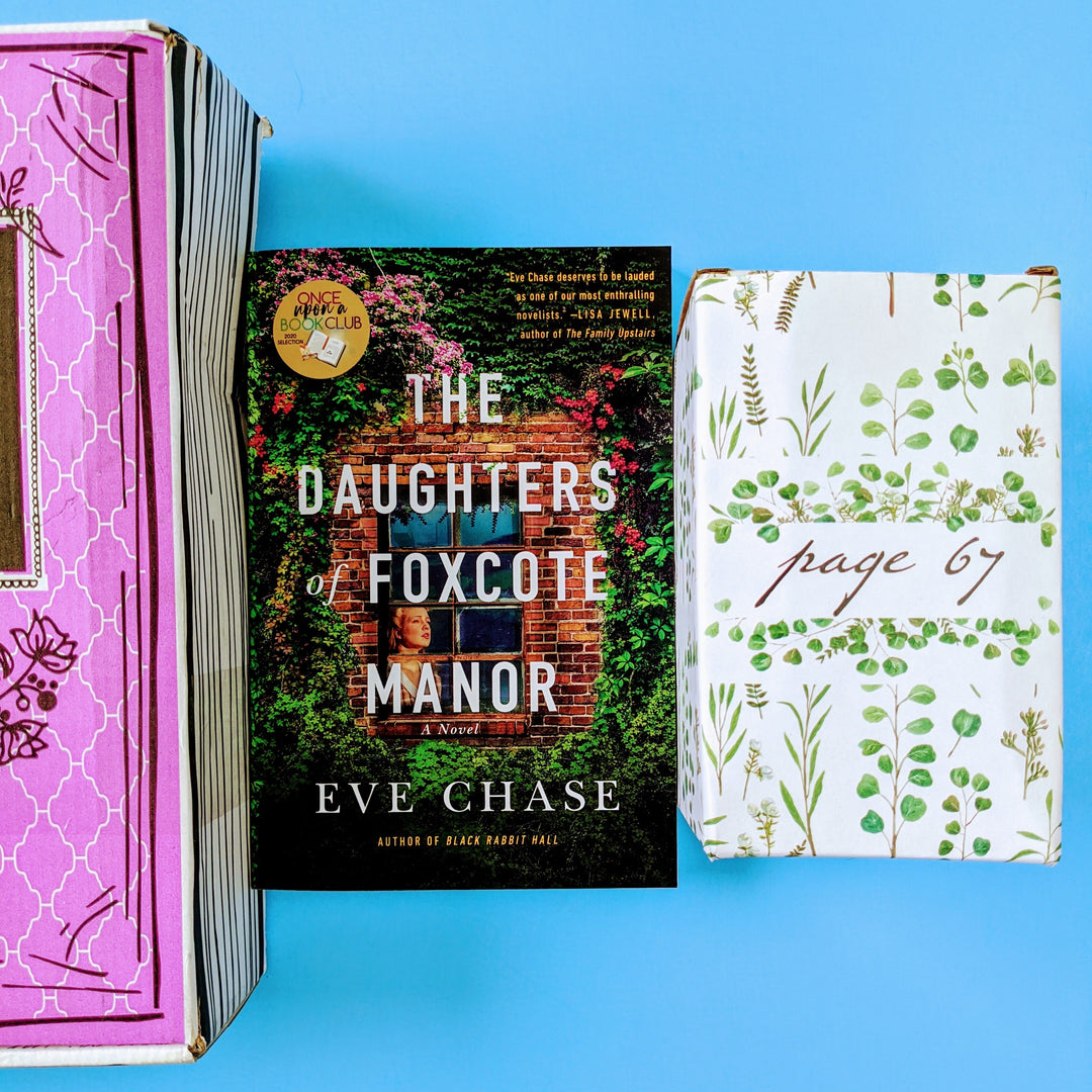 Paperback edition of The Daughters of Foxcote Manor by Eve Chase between a pink box and a white box with a pattern of green leaves on it