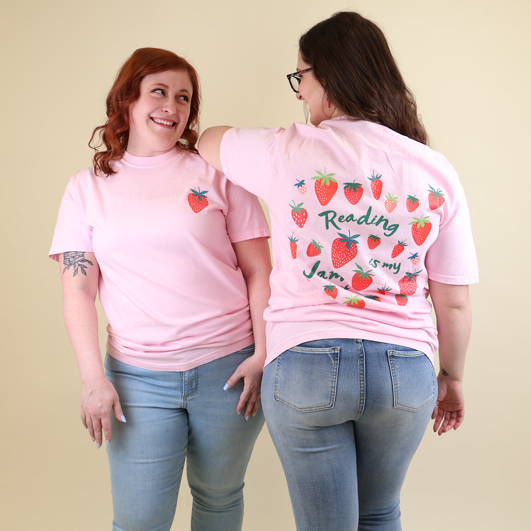 Two women wearing pink t-shirts with strawberry designs and text that says 'Reading is my Jam' on a beige background
