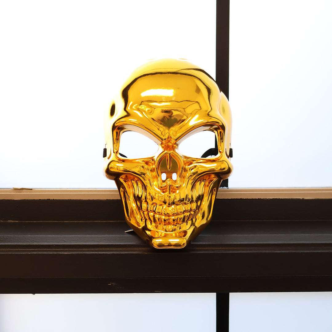 A gold mask sits on a black windowsill.