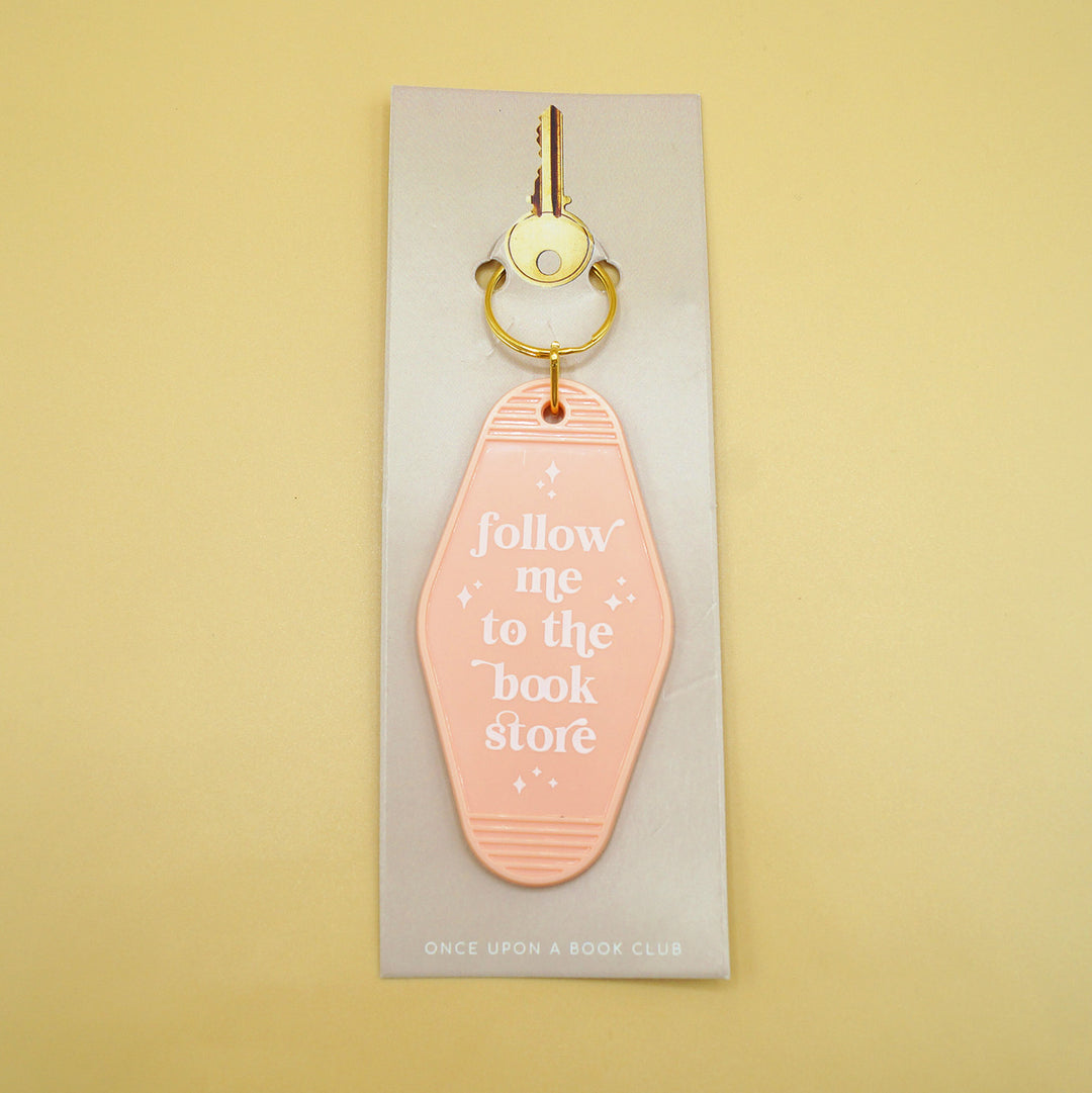 a light peach keychain that says "follow me to the book store" in white writing