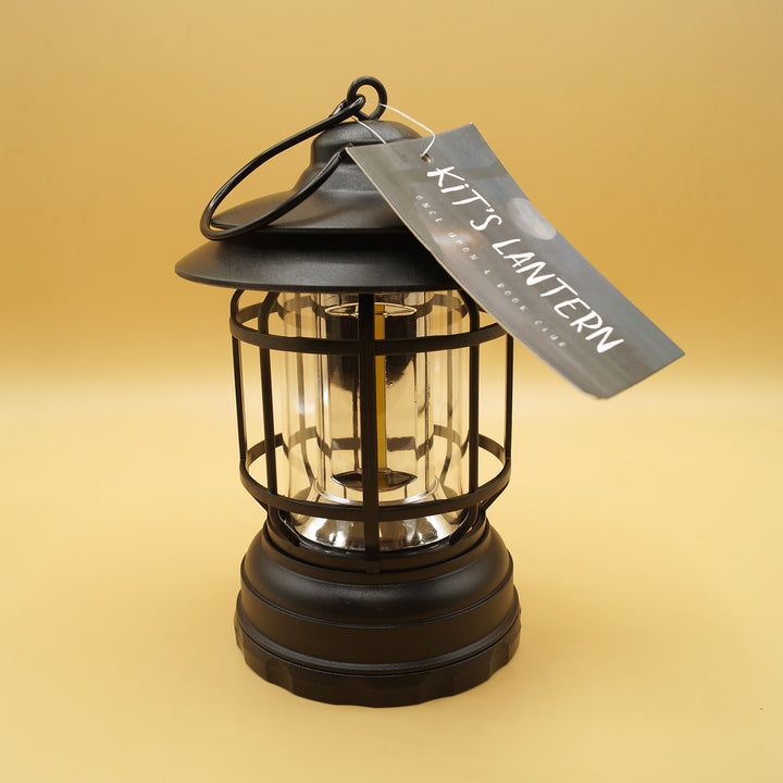 a black hanging lantern with a tag on the top sits on a yellow background
