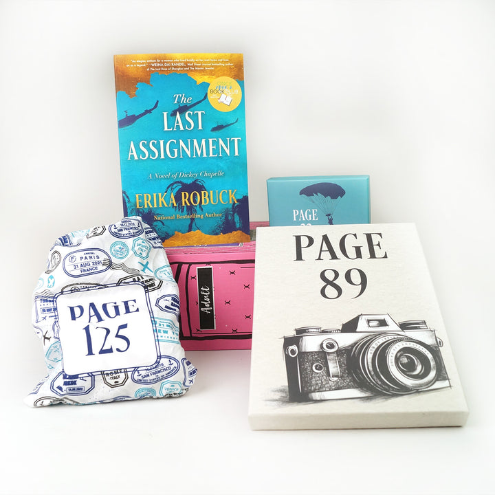 A paperback copy of The Last Assignment by Erika Robuck surrounded by wrapped gifts labeled with page numbers and paper items.