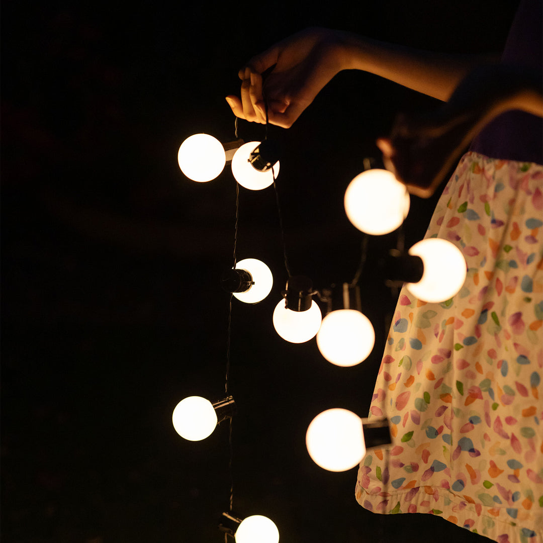 a person holding a set of string lights outside in the dark
