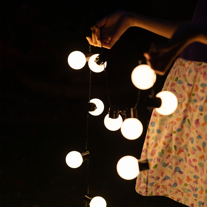 a person holding a set of string lights outside in the dark