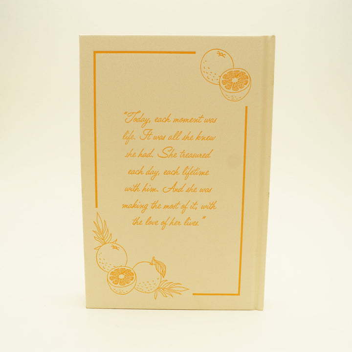 the back of a hardcover pale yellow book with images of oranges on the top right and bottom left. a quote in orange is centered: "Today, each moment was life. It was all she knew she had. She treasured each day, each lifetime with him. And she was making the most of it, with the love of her lives."